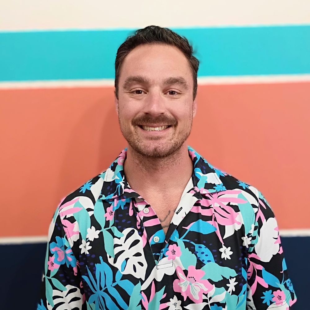 Photo of Dr. Kevin Pisle, chiropractor at Lima Area Spine + Sport, against the clinic's teal and coral accent wall.